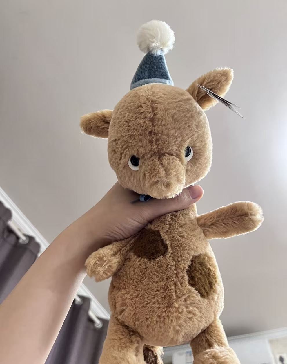 Jellycat Jollipop Giraffe 23cm plush with blue party hat, close-up view