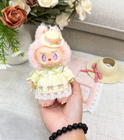Handheld close-up of POP MART MOKOKO plush pendant showing the yellow embroidered dress, lace hem and straw-style hat